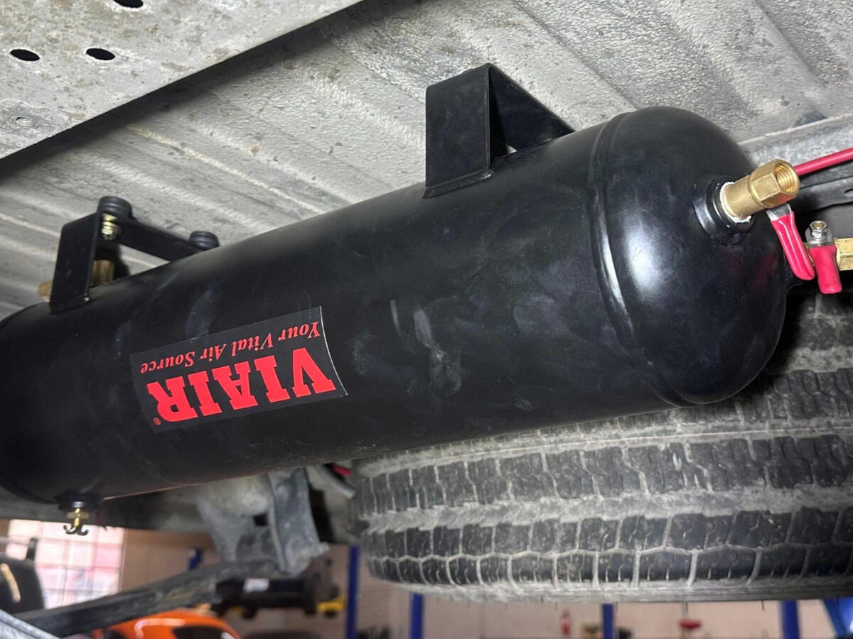 Underbody VIAIR Air Tank Installation Underbody-mounted VIAIR 2.5-gallon compressed air tank installed on a Ram ProMaster camper van for rear air suspension adjustment.